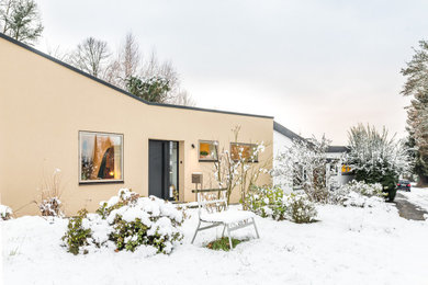 Mittelgroßes, Einstöckiges Modernes Einfamilienhaus mit Putzfassade, brauner Fassadenfarbe und Flachdach in Sonstige