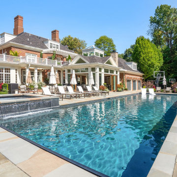 Pool with water feature and spa alongside the glass cabana and shaded lounge ter
