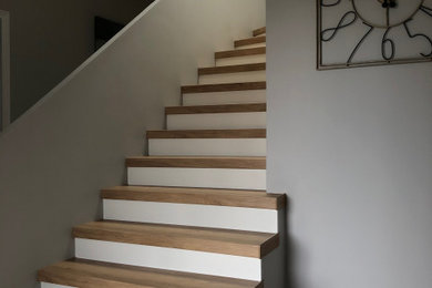 Réalisation d'un grand escalier minimaliste en U avec des marches en bois, des contremarches en bois, un garde-corps en matériaux mixtes, du papier peint et palier.