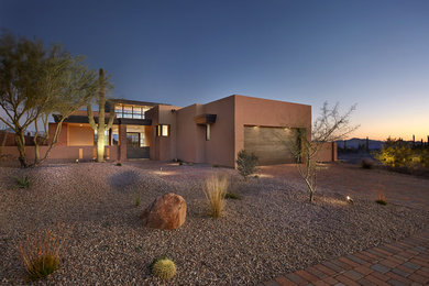 Large trendy brown one-story stucco flat roof photo in Phoenix