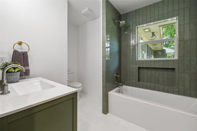 Inspiration for a mid-sized 3/4 green tile and porcelain tile porcelain tile, white floor and single-sink bathroom remodel in Austin with glass-front cabinets, green cabinets, a two-piece toilet, white walls, an integrated sink, solid surface countertops, white countertops and a freestanding vanity