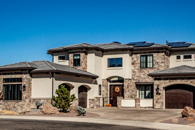 Large tuscan beige three-story stucco house exterior photo in Other with a hip roof and a tile roof