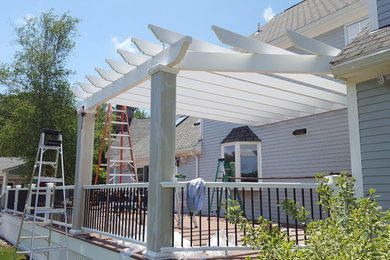 This is an example of an expansive classic back terrace in Boston with a pergola.