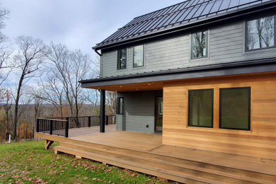 Transitional two-story wood and board and batten exterior home idea in New York with a metal roof and a gray roof