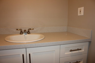 This is an example of a modern bathroom in Vancouver with white cabinets, engineered quartz benchtops and beige walls.
