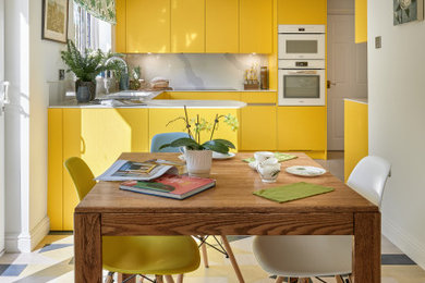 Design ideas for a medium sized contemporary l-shaped kitchen/diner in Hampshire with flat-panel cabinets, yellow cabinets, engineered stone countertops, white splashback, engineered quartz splashback, white appliances, vinyl flooring, no island, multi-coloured floors and white worktops.