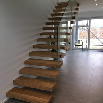 Kragarmtreppe mit Glasgeländer und Stufenverblendern