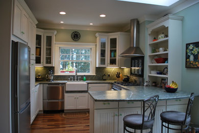 Mid-sized elegant u-shaped laminate floor eat-in kitchen photo in San Francisco with a farmhouse sink, glass-front cabinets, white cabinets, green backsplash, stone slab backsplash, stainless steel appliances and a peninsula