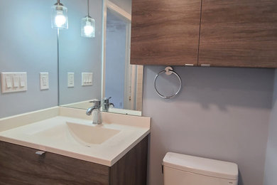 Bathroom - mid-sized modern kids' gray tile and glass tile porcelain tile, brown floor and single-sink bathroom idea in Boston with flat-panel cabinets, medium tone wood cabinets, a two-piece toilet, gray walls, an integrated sink, solid surface countertops, white countertops, a niche and a floating vanity