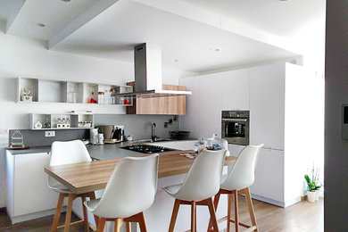 Ispirazione per una cucina contemporanea di medie dimensioni con lavello integrato, ante lisce, ante bianche, top in quarzo composito, paraspruzzi grigio, elettrodomestici in acciaio inossidabile, pavimento in gres porcellanato, penisola, pavimento marrone e top grigio