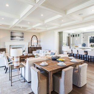 This is an example of a transitional open plan dining in Miami with grey walls, light hardwood floors, a standard fireplace, a stone fireplace surround and beige floor.
