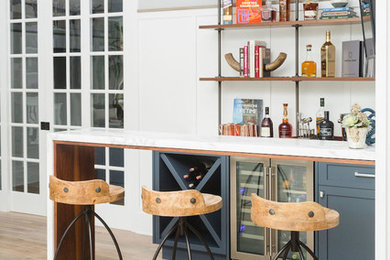 Inspiration for a small transitional single-wall light wood floor and brown floor wet bar remodel in San Diego with shaker cabinets, blue cabinets, marble countertops, white backsplash, wood backsplash and white countertops
