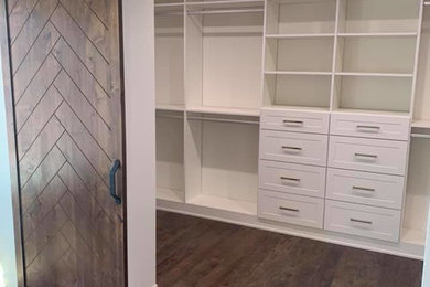 Inspiration for a large farmhouse gender-neutral dark wood floor and brown floor walk-in closet remodel in Phoenix with shaker cabinets and white cabinets