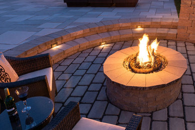 Example of a mid-sized classic backyard stone patio design in New York with a fire pit and no cover