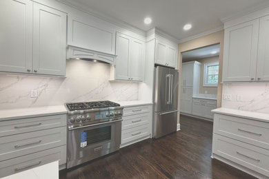 Eat-in kitchen - large transitional dark wood floor and brown floor eat-in kitchen idea in Charleston with a single-bowl sink, shaker cabinets, white cabinets, quartz countertops, white backsplash, quartz backsplash, stainless steel appliances, an island and white countertops