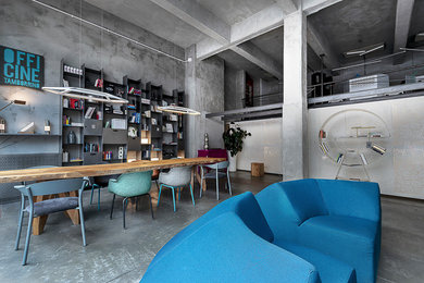 Foto di un ampio soggiorno industriale stile loft con libreria, pareti grigie, pavimento in cemento e pavimento grigio