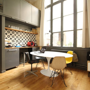 Cette photo montre une salle à manger ouverte sur le salon tendance de taille moyenne avec un mur gris, un sol en bois brun et aucune cheminée.