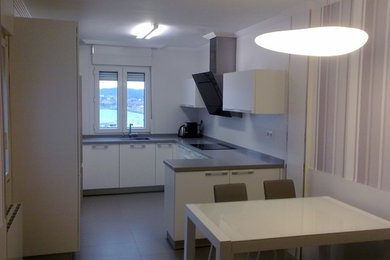 Photo of a mid-sized transitional u-shaped eat-in kitchen in Bilbao with a single-bowl sink, flat-panel cabinets, white cabinets, ceramic floors and no island.
