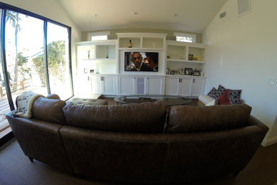 Family room - contemporary medium tone wood floor family room idea in Los Angeles with beige walls and a media wall