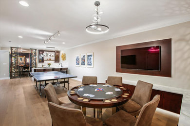 Example of a large transitional walk-out light wood floor basement game room design in DC Metro