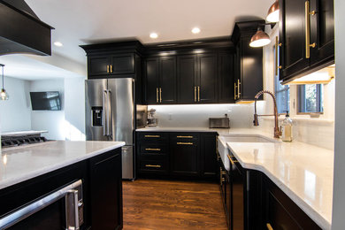 Eat-in kitchen - mid-sized traditional u-shaped medium tone wood floor and brown floor eat-in kitchen idea in Chicago with a farmhouse sink, recessed-panel cabinets, black cabinets, quartzite countertops, white backsplash, subway tile backsplash, stainless steel appliances and white countertops