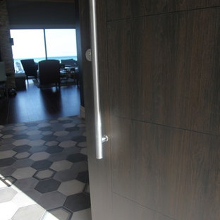 Idées déco pour un hall d'entrée éclectique de taille moyenne avec un mur noir, un sol en carrelage de porcelaine, une porte coulissante, une porte en bois foncé et un sol multicolore.