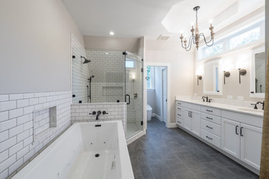 This is an example of a mid-sized transitional master bathroom in Other with recessed-panel cabinets, white cabinets, a freestanding tub, a corner shower, a one-piece toilet, white tile, subway tile, grey walls, ceramic floors, an undermount sink, engineered quartz benchtops, grey floor, a hinged shower door and white benchtops.