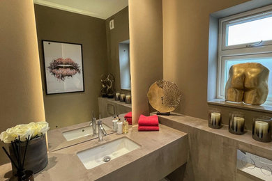 Inspiration for a contemporary powder room in Hertfordshire with brown cabinets, a wall-mount toilet, brown walls, porcelain floors, an integrated sink, concrete benchtops, beige floor, brown benchtops and a floating vanity.