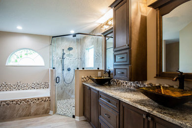 Drop-in bathtub - large transitional master porcelain tile porcelain tile drop-in bathtub idea in Jacksonville with raised-panel cabinets, dark wood cabinets, beige walls, a vessel sink, granite countertops and a hinged shower door