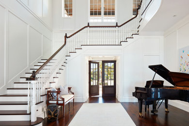 Example of a classic dark wood floor, brown floor, vaulted ceiling and wall paneling double front door design in Other with white walls and a dark wood front door