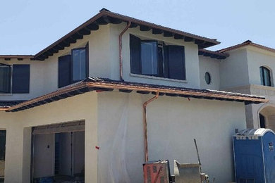 Large trendy beige two-story stucco exterior home photo in Orange County with a shingle roof