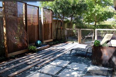 This is an example of a small modern backyard patio in Austin with a water feature, gravel and no cover.