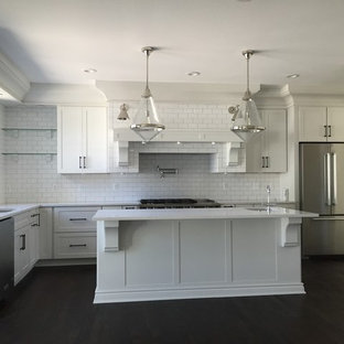 Große Moderne Küche in L-Form mit Vorratsschrank, Doppelwaschbecken, Schrankfronten im Shaker-Stil, weißen Schränken, Quarzwerkstein-Arbeitsplatte, Küchenrückwand in Weiß, Rückwand aus Keramikfliesen, Küchengeräten aus Edelstahl, dunklem Holzboden, Halbinsel und braunem Boden in Huntington