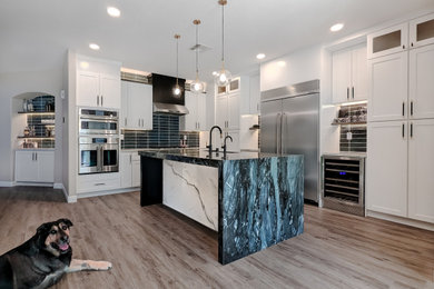 Inspiration for a transitional laminate floor and brown floor eat-in kitchen remodel in Las Vegas with a farmhouse sink, shaker cabinets, white cabinets, quartzite countertops, blue backsplash, ceramic backsplash, stainless steel appliances, an island and blue countertops