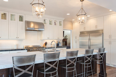 Inspiration for a mid-sized timeless galley medium tone wood floor eat-in kitchen remodel in Salt Lake City with a farmhouse sink, recessed-panel cabinets, white cabinets, limestone countertops, white backsplash, subway tile backsplash and stainless steel appliances