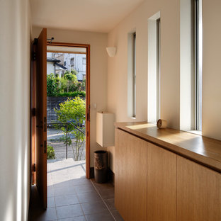 横浜の片開きドアコンテンポラリースタイルのおしゃれな玄関ホール (白い壁、木目調のドア、黒い床) の写真