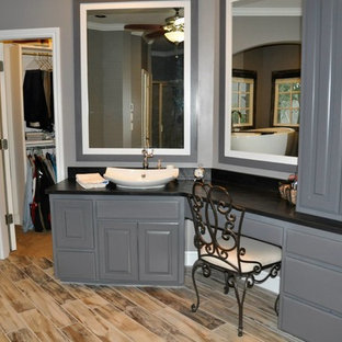 Inspiration pour une grande salle de bain principale craftsman avec un placard avec porte à panneau surélevé, des portes de placard grises, une baignoire indépendante, une douche d'angle, un mur gris, sol en stratifié, une vasque et un plan de toilette en stéatite.