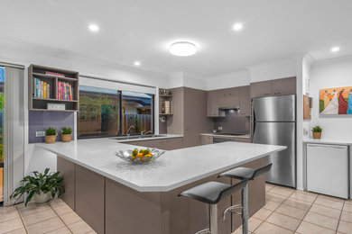 Design ideas for a modern u-shaped kitchen in Brisbane with a drop-in sink, glass sheet splashback and stainless steel appliances.