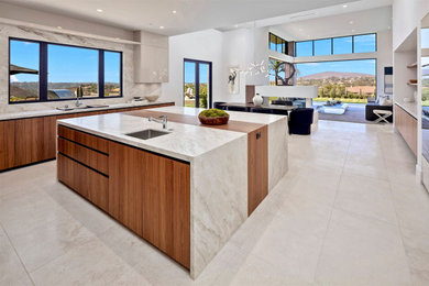 Large trendy u-shaped limestone floor and beige floor open concept kitchen photo in San Diego with a single-bowl sink, flat-panel cabinets, beige cabinets, marble countertops, white backsplash, marble backsplash, stainless steel appliances, an island and white countertops