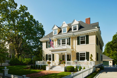 Elegant yellow three-story wood and clapboard house exterior photo in Boston with a hip roof and a shingle roof