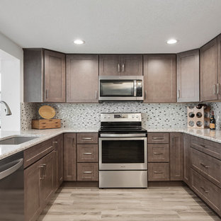 Photo of a mid-sized beach style u-shaped kitchen pantry in Tampa with an undermount sink, shaker cabinets, brown cabinets, granite benchtops, beige splashback, glass tile splashback, stainless steel appliances, ceramic floors, no island, beige floor and beige benchtop.