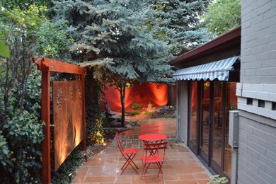 Inspiration for a mid-sized asian backyard patio in Denver with natural stone pavers and a water feature.