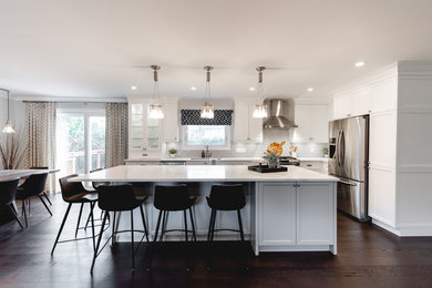 Large transitional l-shaped brown floor open concept kitchen photo in Montreal with a single-bowl sink, shaker cabinets, white cabinets, quartzite countertops, gray backsplash, subway tile backsplash, stainless steel appliances, an island and white countertops