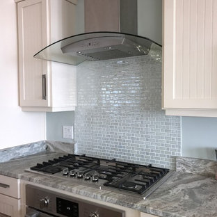 This is an example of a small modern single-wall kitchen pantry in New York with white cabinets, quartz benchtops, metallic splashback, glass tile splashback and stainless steel appliances.