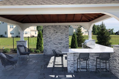 Photo of a large transitional backyard patio in New York with an outdoor kitchen, concrete pavers and a gazebo/cabana.