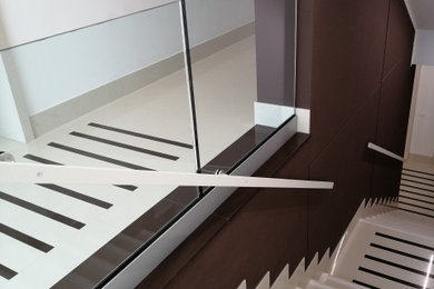 Immagine di una grande scala a rampa dritta minimalista con pedata in marmo, alzata in marmo e parapetto in vetro