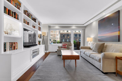 Inspiration for a mid-sized transitional enclosed medium tone wood floor living room remodel in New York with gray walls, no fireplace and a media wall