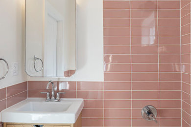 Idéer för att renovera ett mellanstort 50 tals badrum, med möbel-liknande, skåp i ljust trä, ett badkar i en alkov, en dusch i en alkov, en toalettstol med separat cisternkåpa, rosa kakel, porslinskakel, vita väggar, klinkergolv i porslin, ett integrerad handfat, rosa golv och med dusch som är öppen