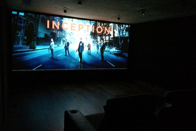 На фото: большой изолированный домашний кинотеатр в современном стиле с коричневыми стенами, темным паркетным полом, проектором и коричневым полом с