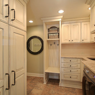 Diseño de lavadero multiusos y en L, tradicional, de tamaño medio, con fregadero bajoencimera, armarios con paneles con relieve, puertas de armario con efecto envejecido, encimera de granito, paredes verdes y lavadora y secadora juntas